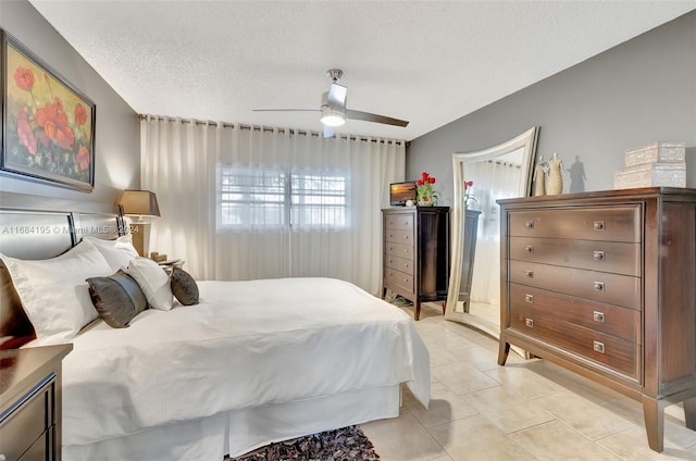 bedroom featuring a textured ceiling, light tile patterned floors, and ceiling fan