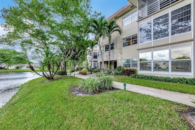 view of property's community with a water view and a lawn