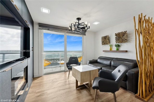 living room featuring a healthy amount of sunlight, a notable chandelier, a water view, and light hardwood / wood-style floors