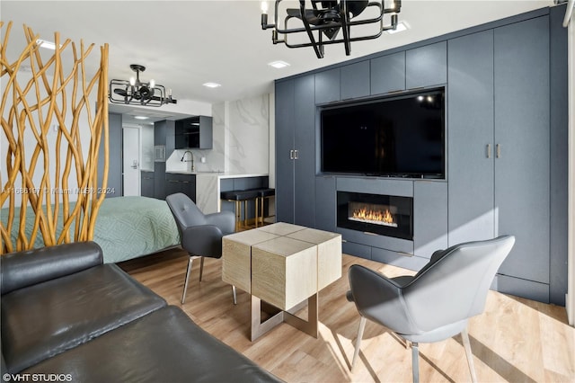 living room featuring light hardwood / wood-style flooring, a notable chandelier, and sink