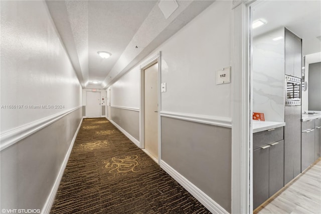 hall with hardwood / wood-style flooring and a textured ceiling