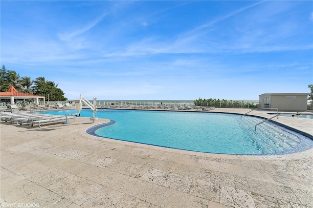 view of swimming pool featuring a patio area and a water view