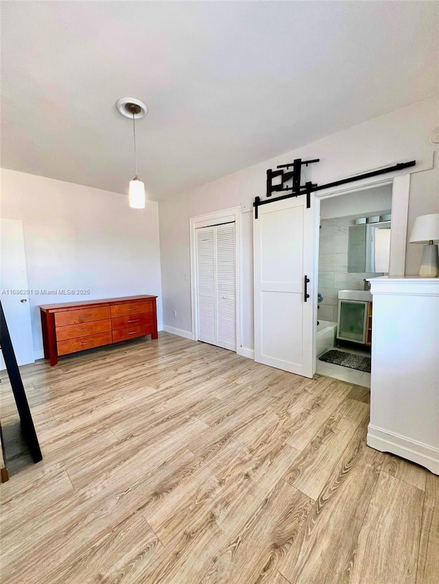 unfurnished dining area with a barn door, wood finished floors, and baseboards