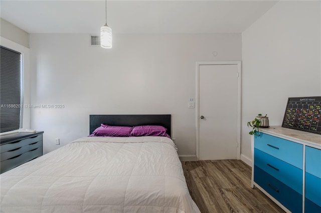 bedroom with dark wood-style flooring, visible vents, and baseboards