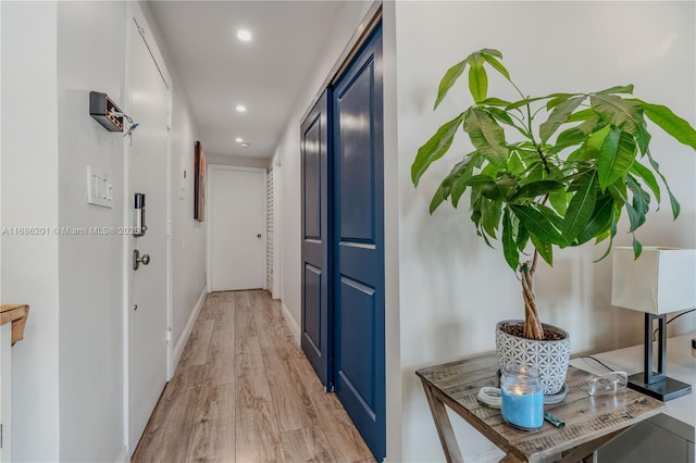 corridor featuring light wood-style flooring, baseboards, and recessed lighting