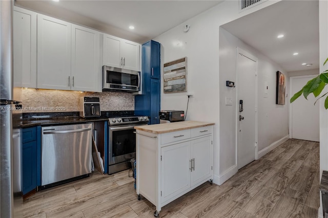 kitchen with blue cabinetry, visible vents, backsplash, light wood-style flooring, and appliances with stainless steel finishes