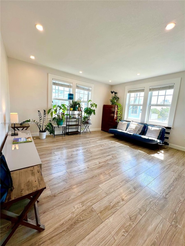 living area with baseboards, light wood-type flooring, and recessed lighting