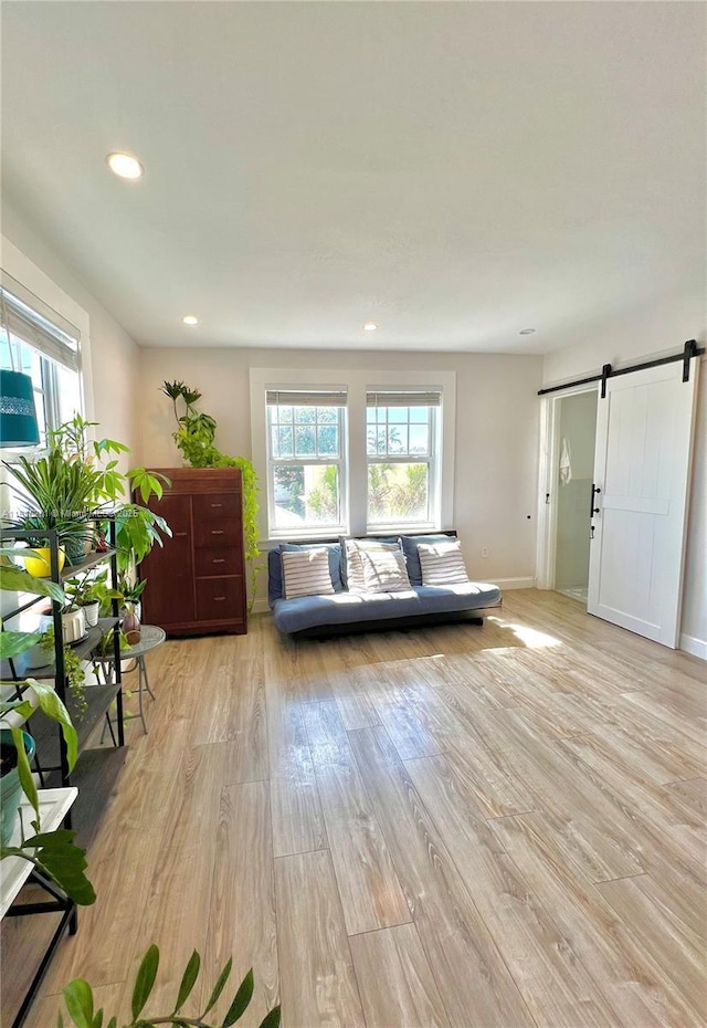 unfurnished living room featuring recessed lighting, baseboards, light wood finished floors, and a barn door