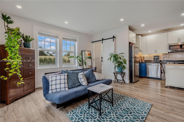 living room with a barn door and light hardwood / wood-style floors