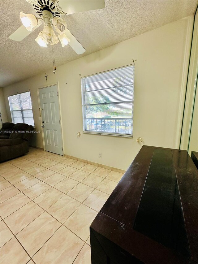 interior space featuring ceiling fan, a textured ceiling, and light tile patterned floors