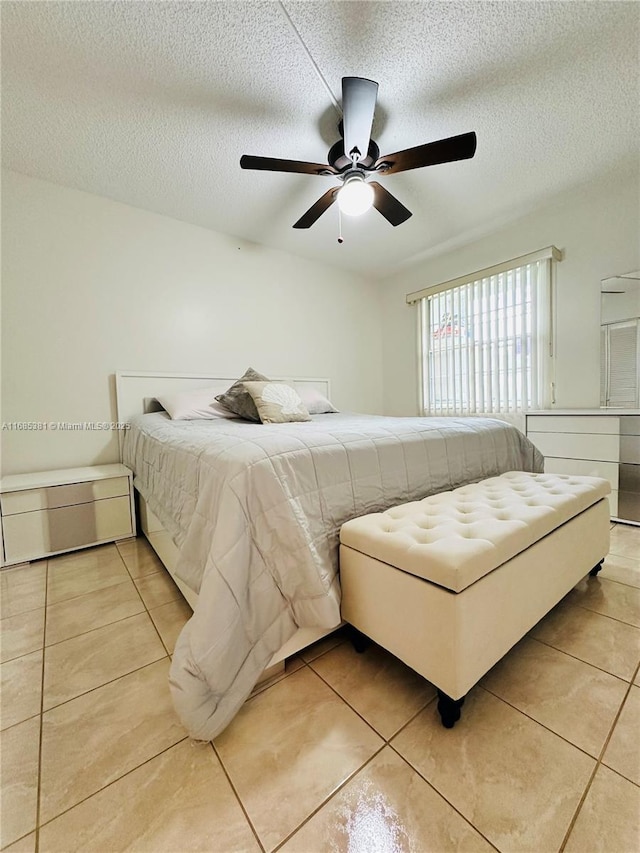 tiled bedroom featuring ceiling fan and a textured ceiling