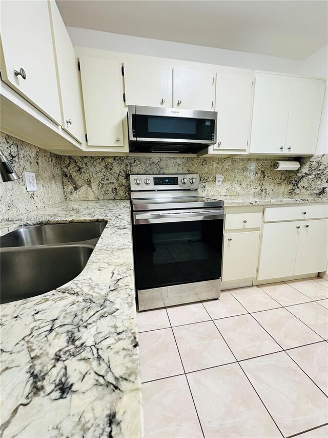 kitchen with sink, white cabinets, stainless steel appliances, and light tile patterned flooring