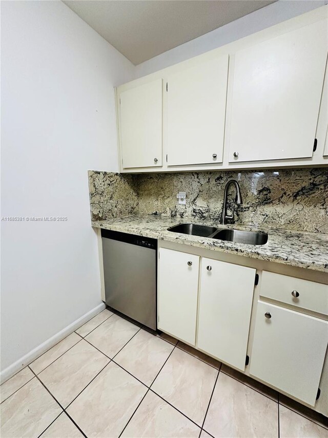 kitchen featuring stainless steel dishwasher, white cabinets, sink, and light tile patterned floors