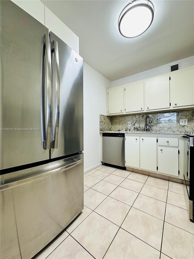 kitchen with decorative backsplash, white cabinetry, appliances with stainless steel finishes, and light tile patterned flooring