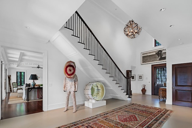 staircase featuring ornamental molding, hardwood / wood-style floors, and ceiling fan with notable chandelier