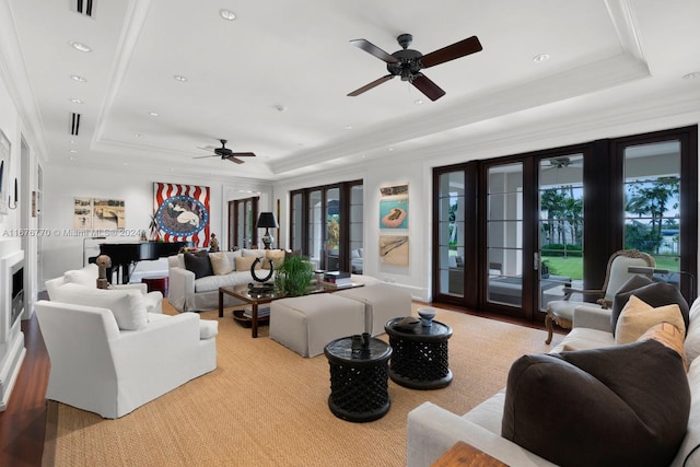 living room with crown molding, ceiling fan, and a raised ceiling