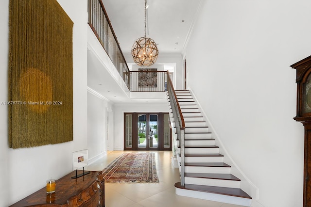 entryway with french doors, ornamental molding, a notable chandelier, and a high ceiling