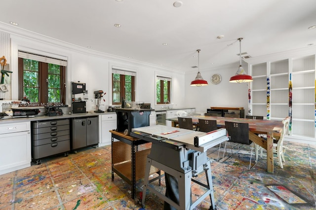 kitchen with a wealth of natural light, crown molding, white cabinetry, and hanging light fixtures