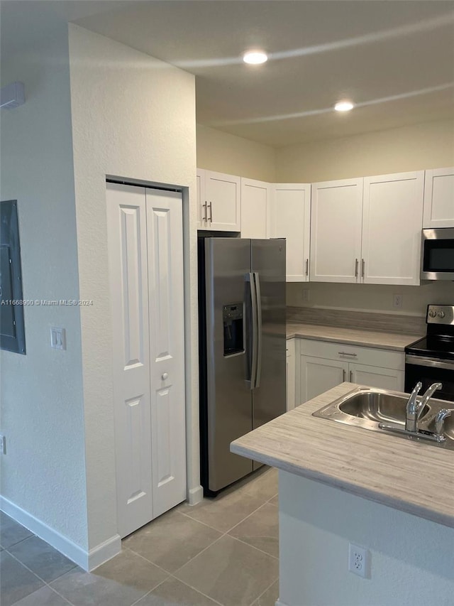 kitchen featuring electric panel, white cabinets, stainless steel appliances, and light tile patterned floors