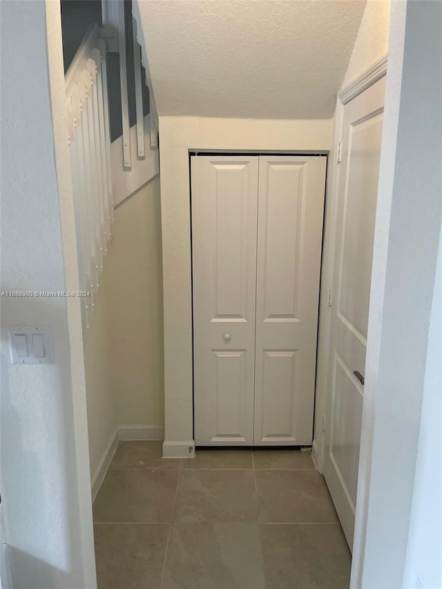 hall with tile patterned flooring and a textured ceiling