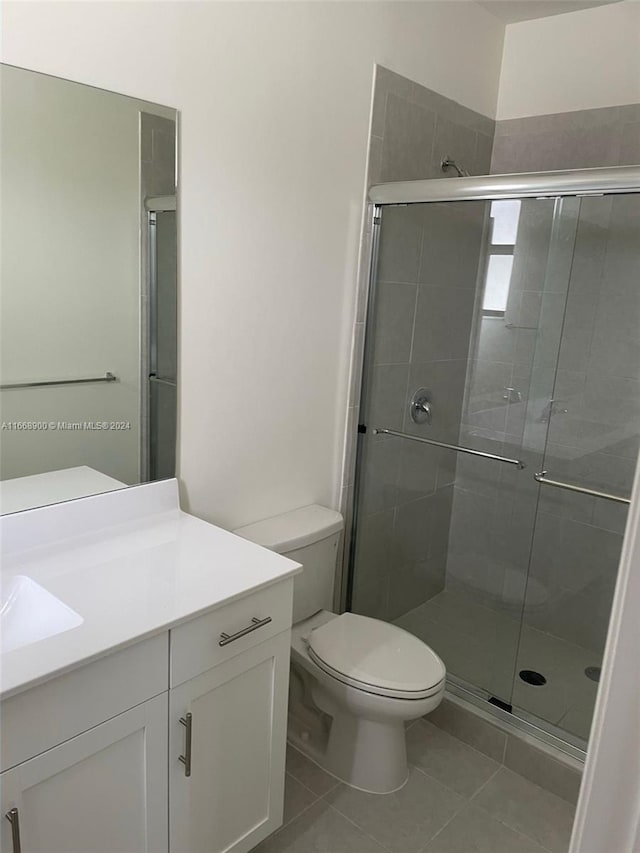 bathroom with tile patterned floors, walk in shower, vanity, and toilet