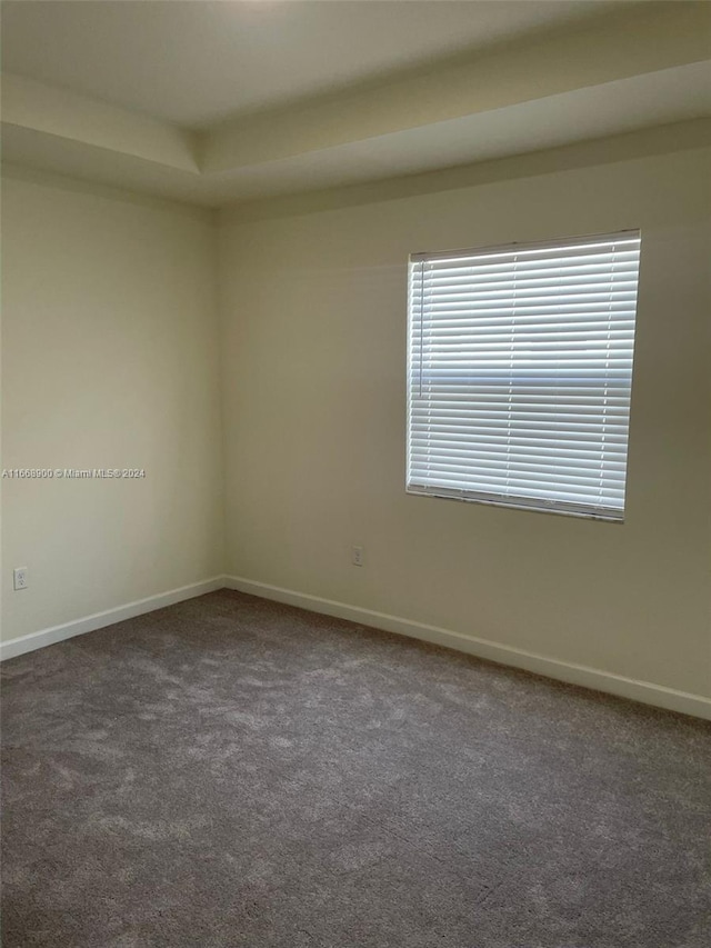 spare room with dark carpet