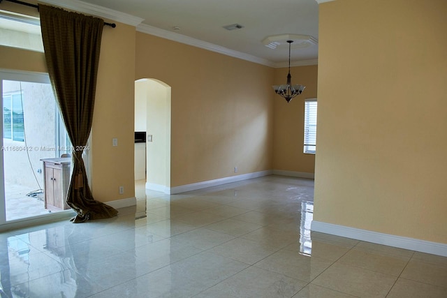 tiled spare room featuring crown molding, a wealth of natural light, and an inviting chandelier