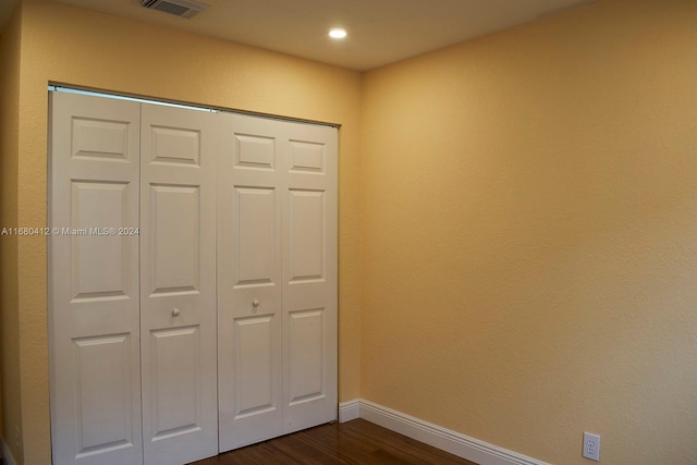 unfurnished bedroom featuring a closet and dark wood-type flooring