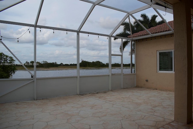 view of patio / terrace featuring a lanai and a water view