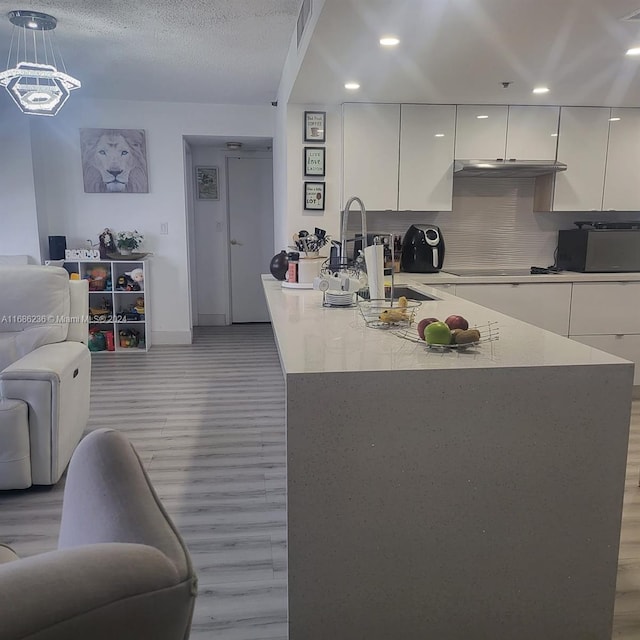 kitchen featuring decorative backsplash, sink, decorative light fixtures, white cabinets, and a textured ceiling