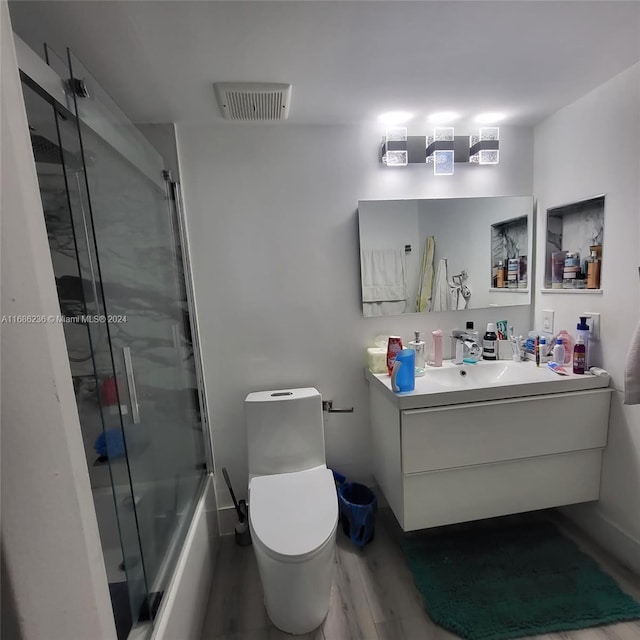 full bathroom with vanity, toilet, combined bath / shower with glass door, and hardwood / wood-style floors