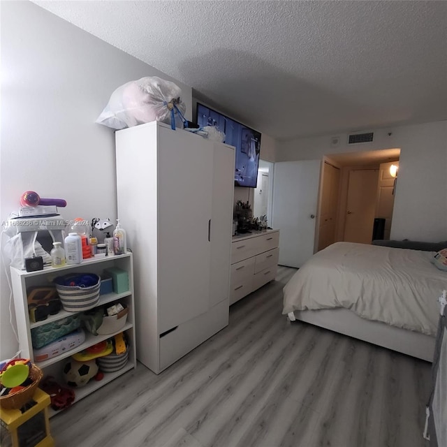 bedroom featuring light hardwood / wood-style flooring and a textured ceiling