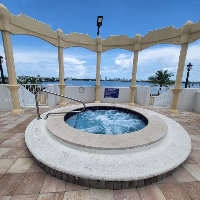 view of swimming pool with a water view and a hot tub