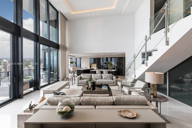 living room featuring concrete floors, a tray ceiling, expansive windows, and a high ceiling