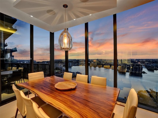 dining area featuring expansive windows, a water view, and light tile patterned floors