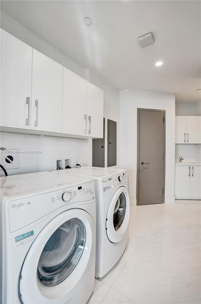 laundry room with light tile patterned floors, separate washer and dryer, and cabinets