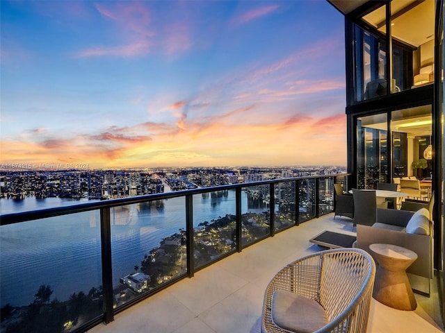 balcony at dusk featuring a water view