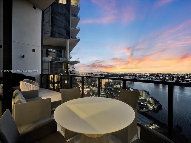 balcony at dusk with an outdoor living space and a water view