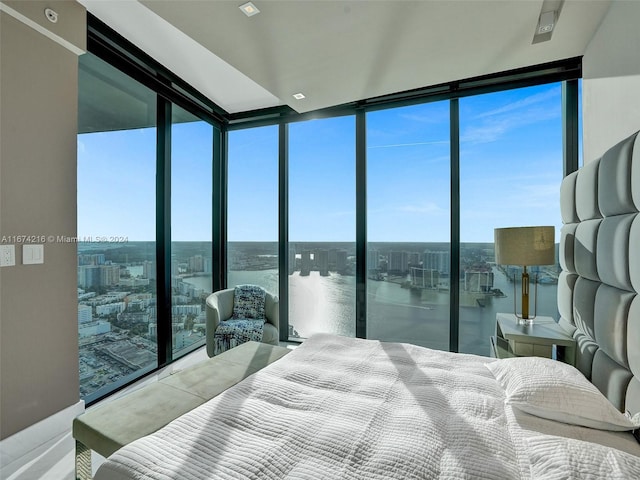 bedroom featuring floor to ceiling windows, multiple windows, and a water view