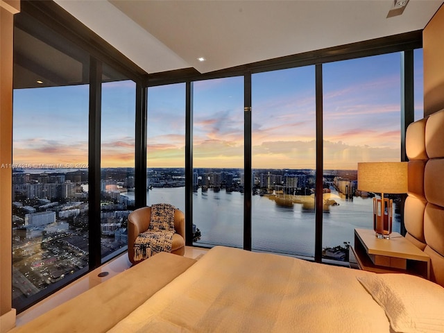 bedroom featuring floor to ceiling windows, multiple windows, and a water view