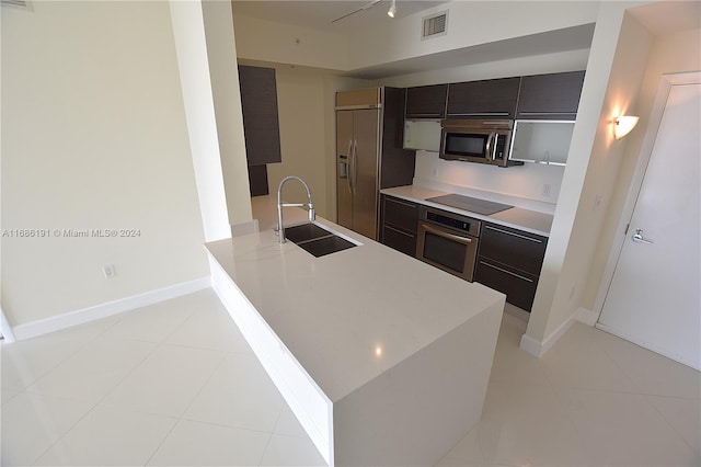 kitchen featuring light tile patterned flooring, appliances with stainless steel finishes, dark brown cabinets, and sink