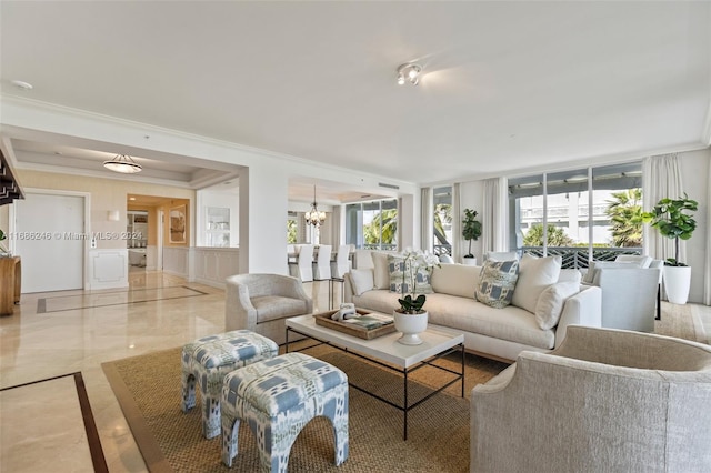 living room with crown molding, a wealth of natural light, and an inviting chandelier