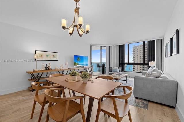 dining space featuring an inviting chandelier, a wall of windows, and light wood-type flooring