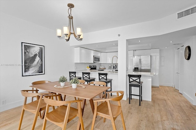 dining space with light hardwood / wood-style flooring and a chandelier