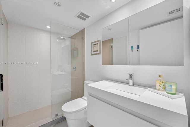 bathroom featuring vanity, toilet, and a shower with shower door