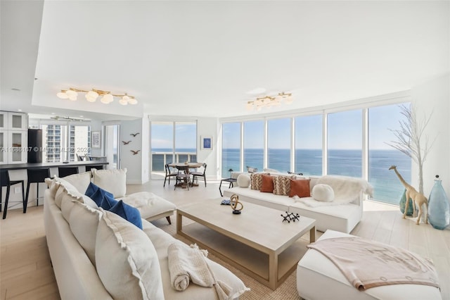 living room featuring light hardwood / wood-style floors, a water view, and a wealth of natural light