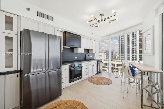 kitchen featuring appliances with stainless steel finishes, decorative backsplash, sink, light hardwood / wood-style floors, and white cabinets