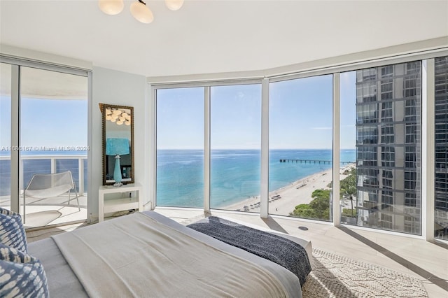 bedroom featuring hardwood / wood-style flooring, multiple windows, a view of the beach, and a water view