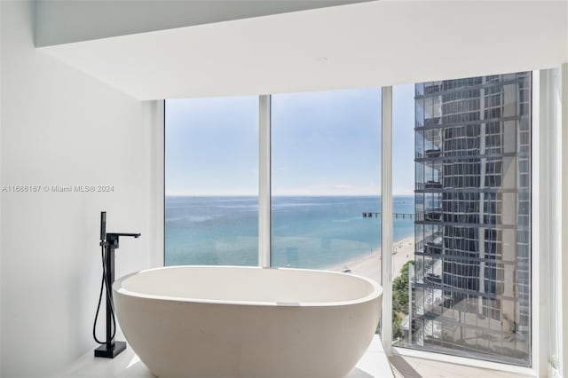 bathroom with a water view, a view of the beach, and a bathing tub