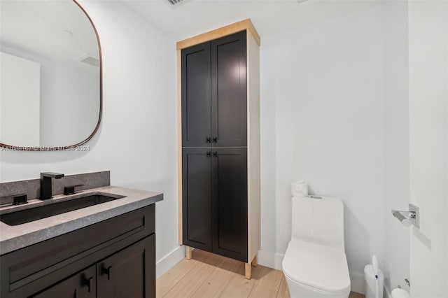 bathroom featuring vanity, hardwood / wood-style flooring, and toilet